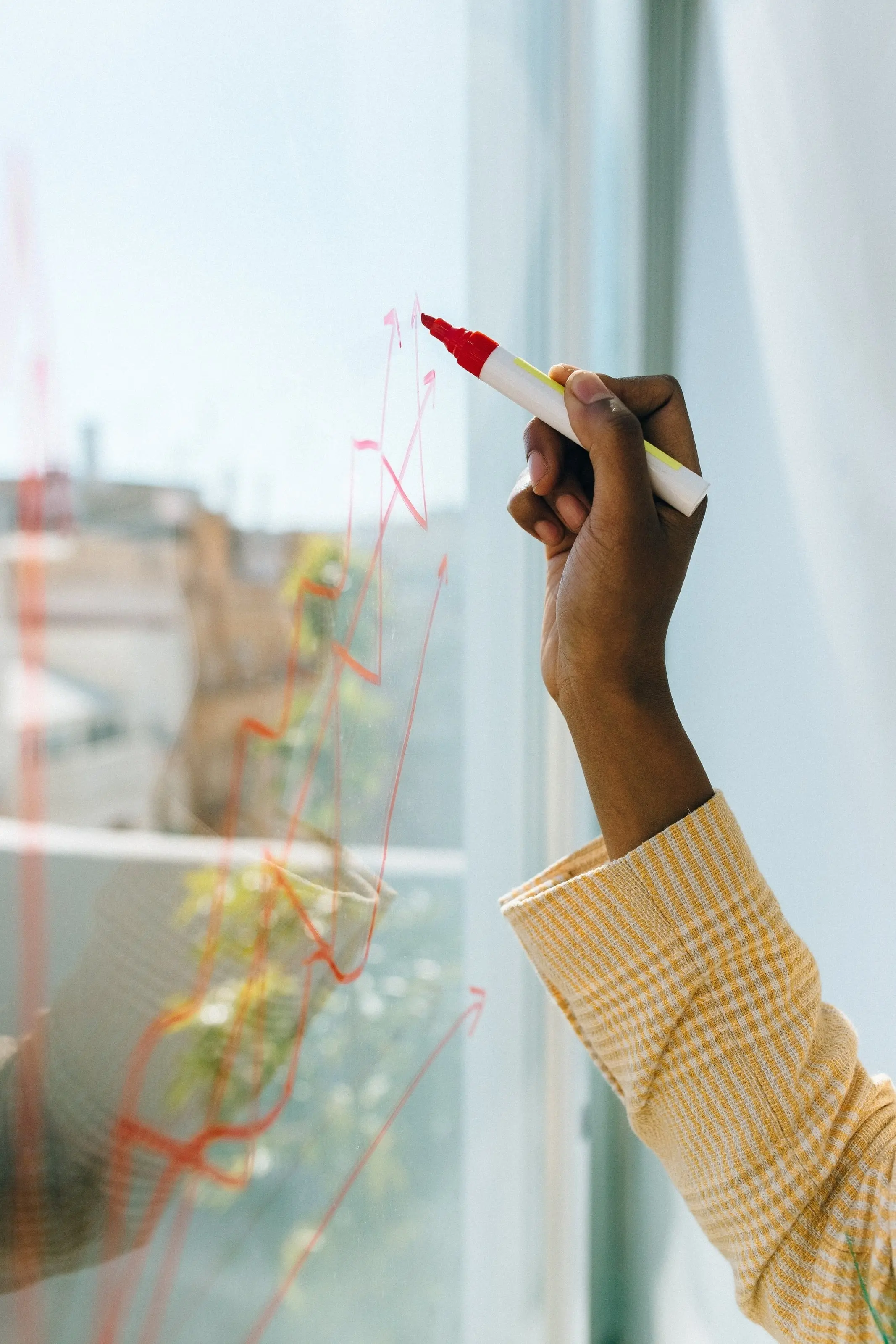 A hand writing with a marker on a glass wall